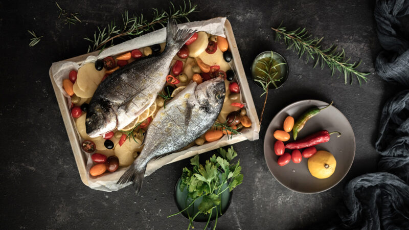 Raw of sea bream and croaker fish with mango and green olives
